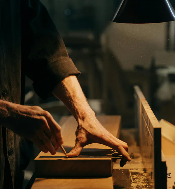 Industrial measurement scene showing a worker using a precision measuring instrument to measure and mark material on a workbench, demonstrating the practical application of measuring instruments in manufacturing and processing.