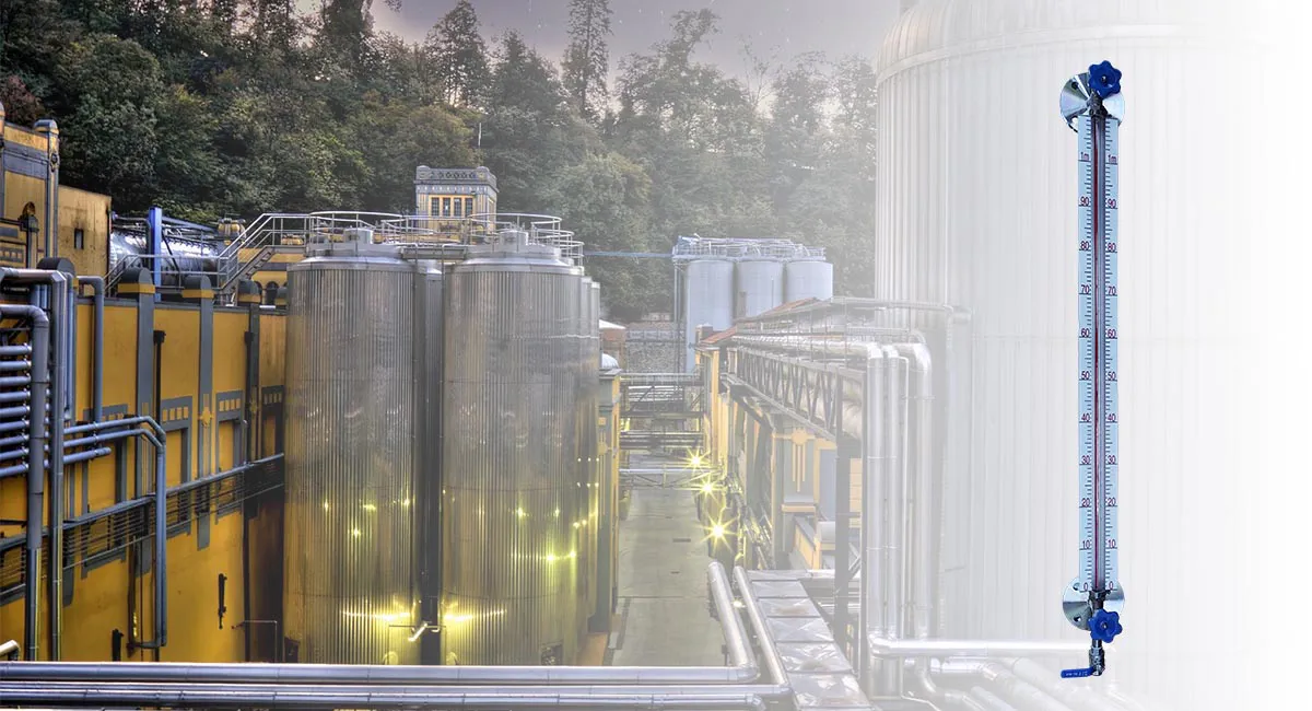 Glass tube liquid level gauge mounted beside large industrial storage tanks for continuous level monitoring.