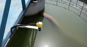 Transmisor ultrasónico de nivel de líquido instalado en un depósito de aguas residuales para medir el nivel sin contacto