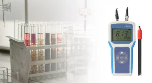 Digital pH meter for laboratory testing with multiple test tubes in the background.