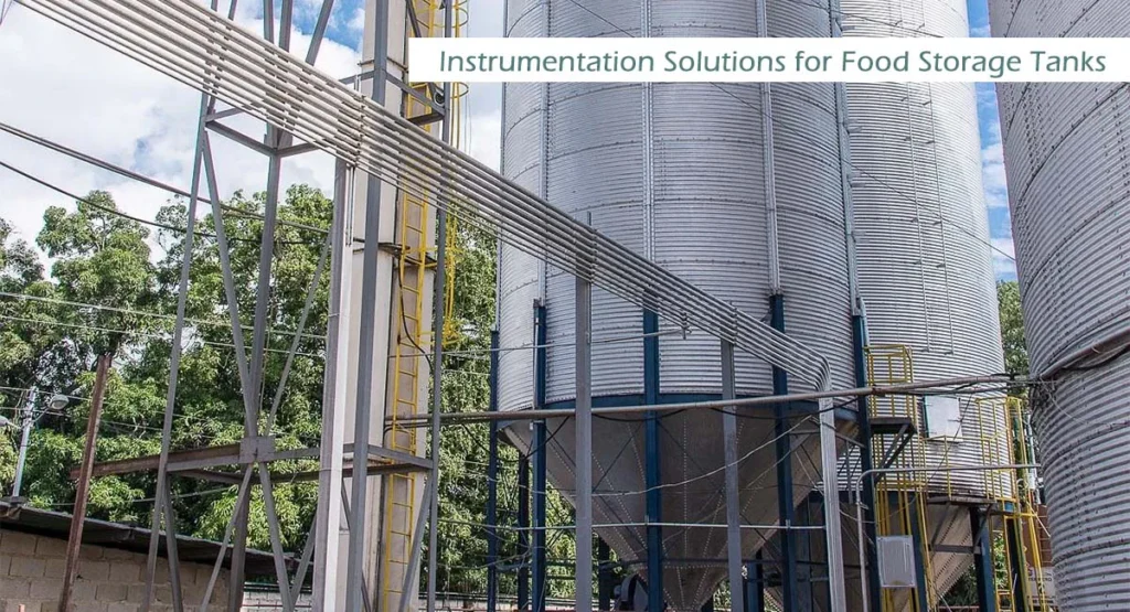 Large industrial storage tanks and silos at a modern food processing plant, showcasing professional instrumentation solutions for food industry level monitoring