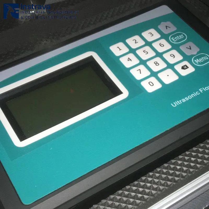 Крупный план панели управления промышленного ультразвукового расходомера жидкости с ЖК-экраном и 16-разрядной клавиатурой.