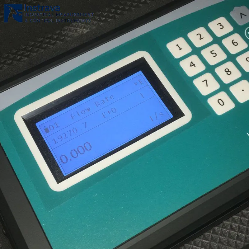 Портативный ультразвуковой расходомер во включенном состоянии, экран с голубой подсветкой, отображающий данные о расходе в реальном времени.