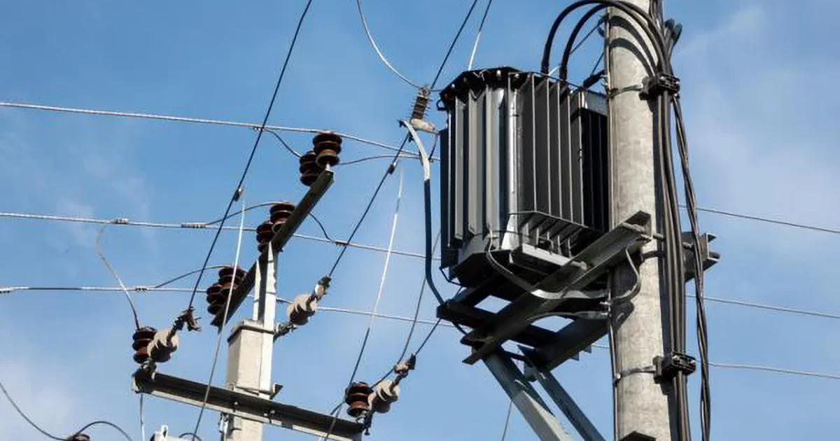 Outdoor pole-mounted distribution transformer used in electrical power grid for voltage conversion and power supply stability