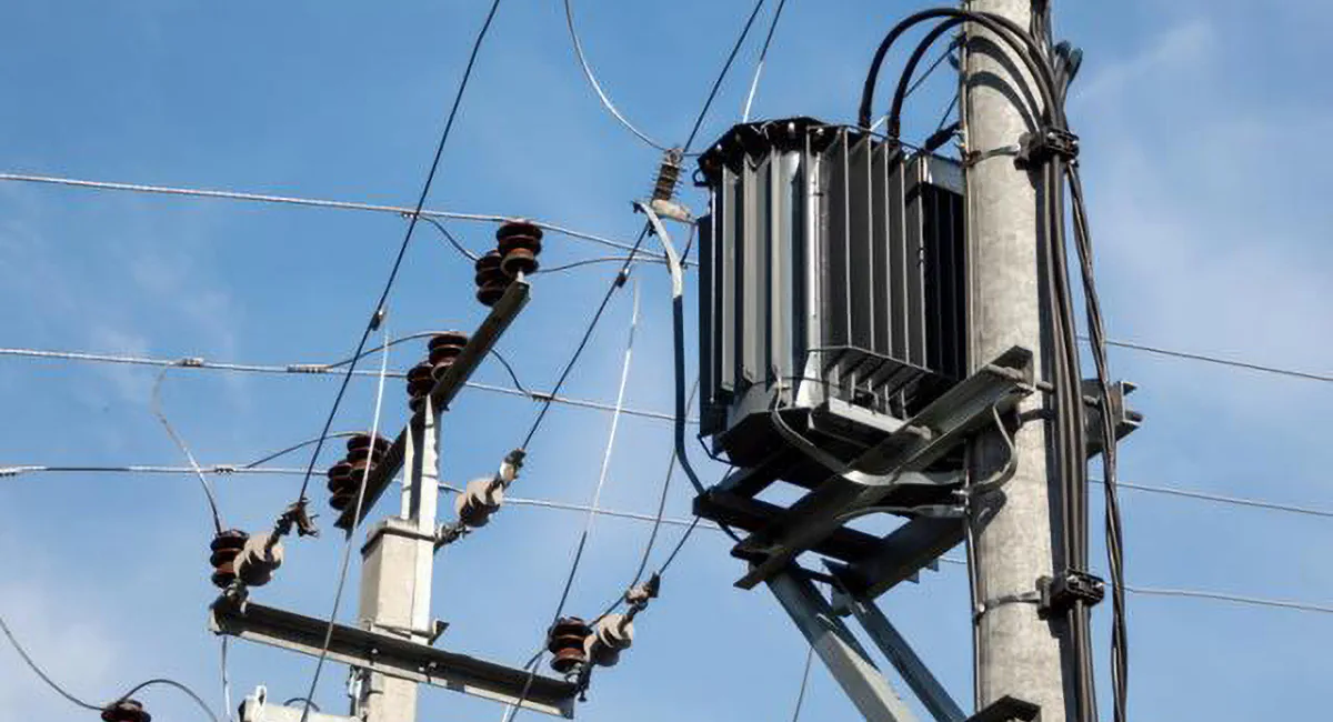 Outdoor pole-mounted distribution transformer used in electrical power grid for voltage conversion and power supply stability
