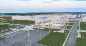An aerial view of a large industrial equipment manufacturing plant or energy facility, surrounded by roads and infrastructure.