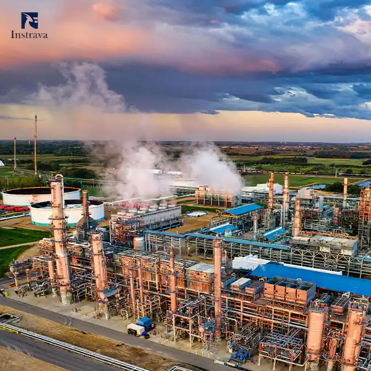 Aerial wide shot of large-scale petrochemical refinery plant at sunset sky, with distillation towers, storage tanks, dense process pipeline network and steam emission, Instrava industrial measurement & control instrumentation application scenario for oil & gas refining industry