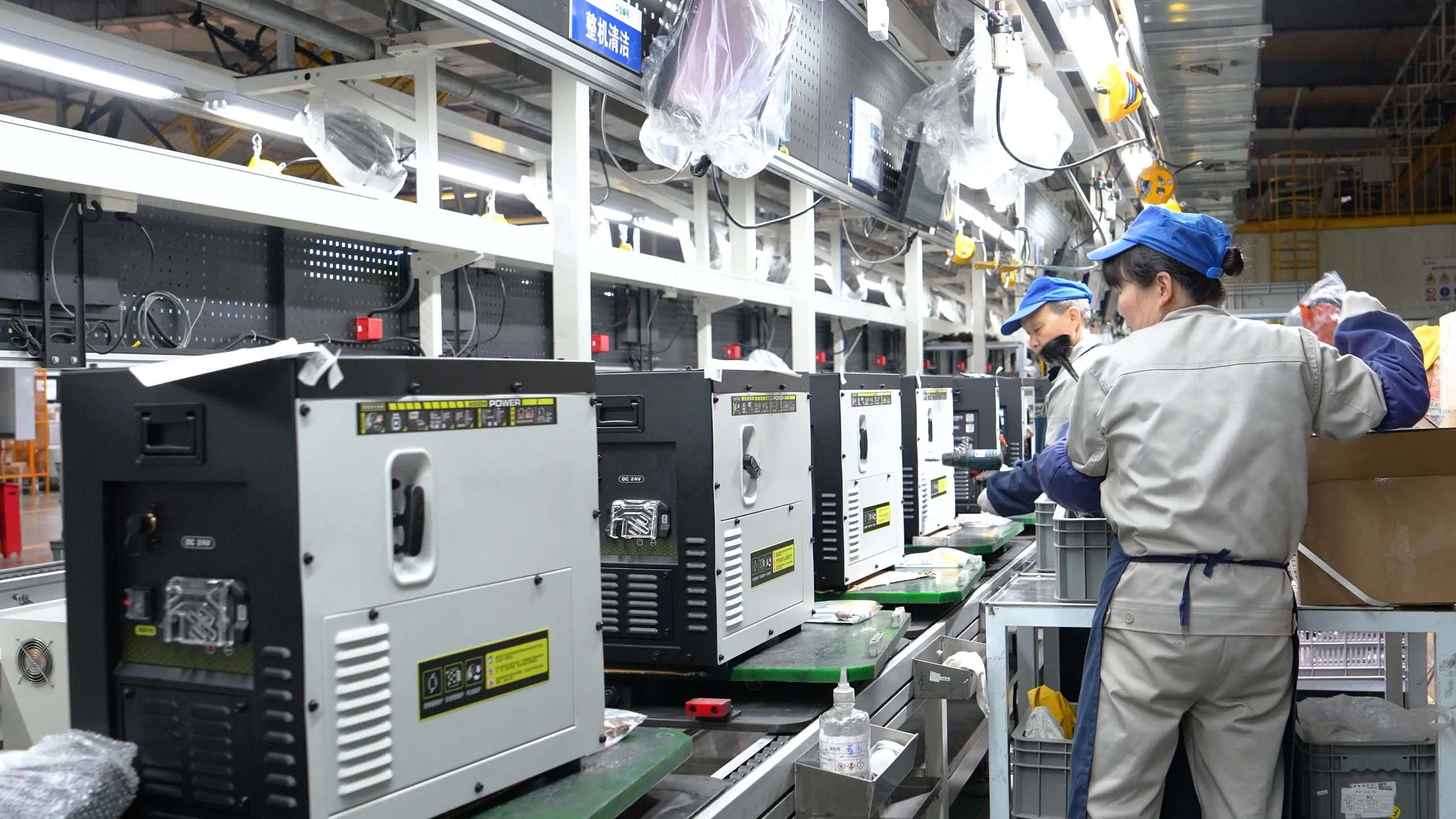 Dual fuel quiet inverter generator production line with industrial assembly workers.